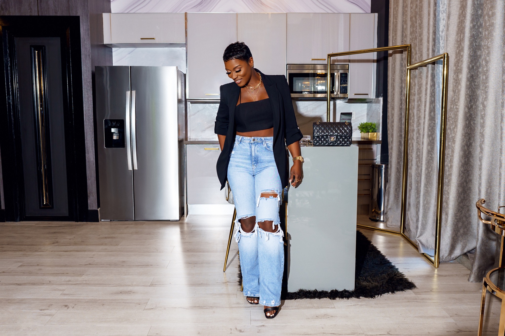 Full-length photo of Mela in a black blazer in an ivory and gold interior